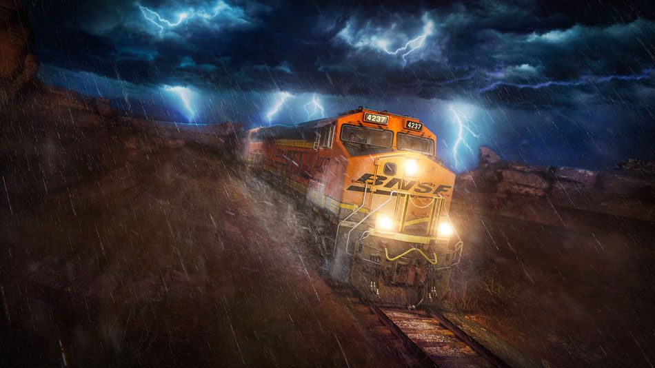 In this colour still from Train Sim World 3 a BNSF ES44C4 locomotive in its usual orange livery powers through the Cajon Pass in heavy rain. Lightning rages overhead.