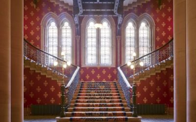 The grand staircase at the St Pancras hotel is profusely decorated and lit with slender Gothic windows.