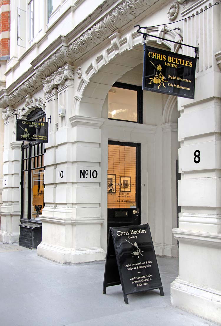 This colour photograph shows the Chris Beetles gallery on Ryder Street, St James’s, resplendent with rusticated façade, fluted pilasters and composite capitals. Large arched windows with black frames flank a grand entrance archway. Two black hanging signs with gold lettering identify the venue.
