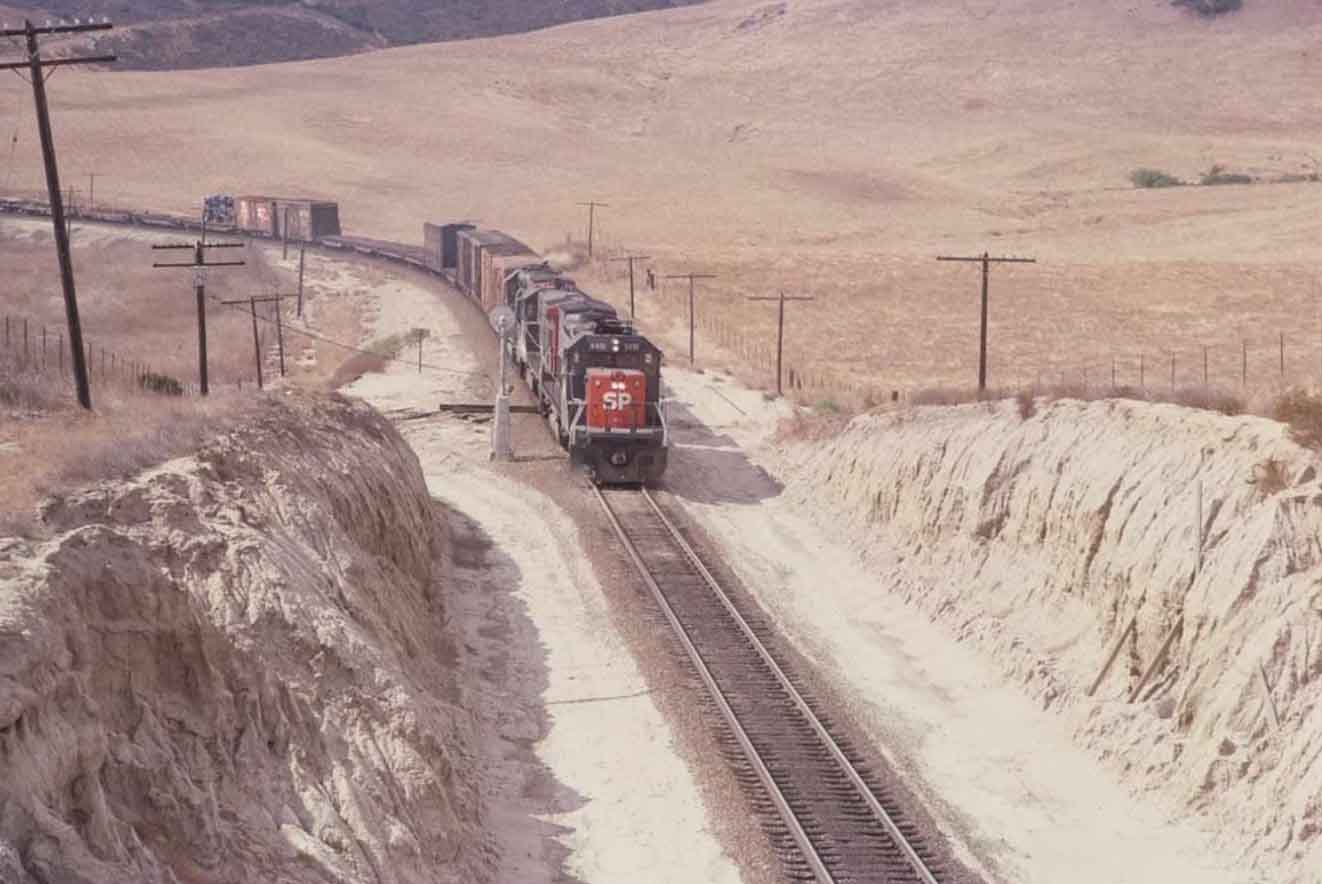 In this colour photo from the 1980s Southern Pacific’s SD70 locomotive 8491 hauls cargo up a gradient in the New Mexico desert.