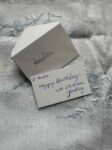 Colour photograph of a miniature envelope and gift card with a handwritten message.
